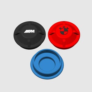 Pode incluir: Três tampas automotivas: uma preta com o logotipo "M" branco, uma vermelha com o logotipo da BMW e uma azul. As tampas são circulares com um centro rebaixado e pequenas abas.