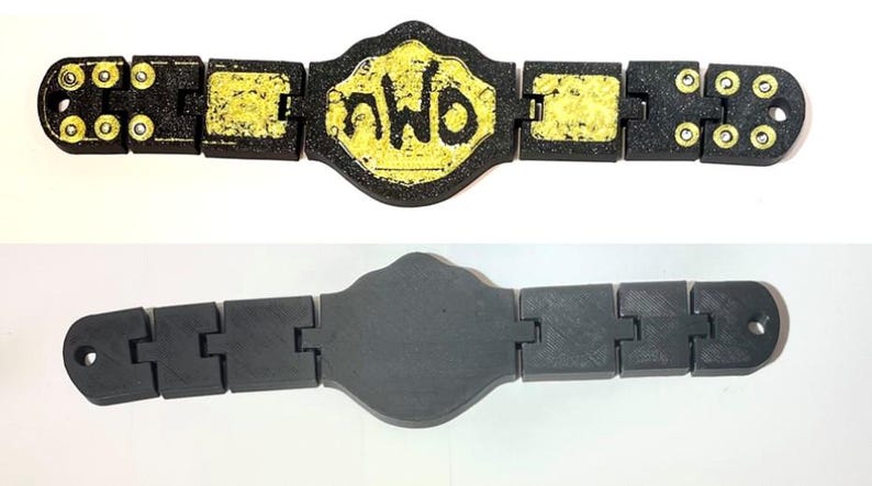 May include: A black and yellow championship belt featuring the letters "nWo" on the central plate. The belt is constructed from linked rectangular sections. A grey version of the belt is shown below.