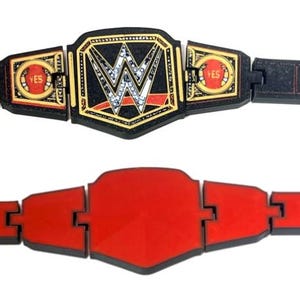 May include: Two toy championship belts. The top belt is black with gold accents and the WWE logo. The bottom belt is red. Both belts are made of connected segments.
