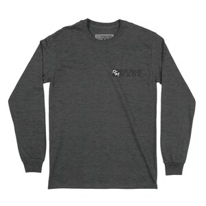 May include: Dark gray long-sleeve shirt with the text "BLUE COLLAR MADE" printed on the front. The shirt has a crew neck and ribbed cuffs. The text is in white and black. The shirt is made of a soft, comfortable material.