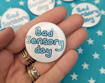May include: A white button with blue text that reads "Bad Sensory Day".