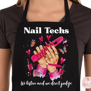 May include: Black apron with the text "Nail Techs" at the top. The apron features a graphic of hands with long, pink nails, nail polish bottles, butterflies, and hearts. The text "We listen and we don't judge" is at the bottom.