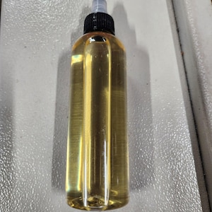 May include: A clear glass bottle with a black cap and a dropper tip, filled with a light yellow liquid.