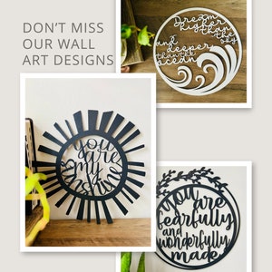 Puede incluir: Tres piezas de arte de pared de madera en blanco y negro con citas inspiradoras. La primera pieza es un sol con las palabras "You are my sunshine". La segunda pieza es un c&iacute;rculo con las palabras "Dream higher and deeper than the ocean sky". La tercera pieza es un c&iacute;rculo con hojas alrededor del borde y las palabras "You are fearfully and wonderfully made".