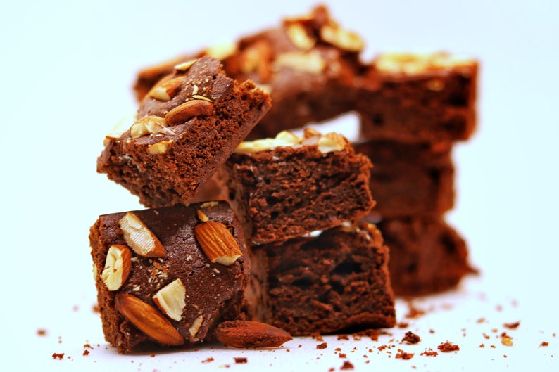 Peut inclure: Une pile de brownies au chocolat garnis d'amandes. Les brownies sont d'une couleur brun fonc&eacute; riche et ont une texture l&eacute;g&egrave;rement croustillante. Les amandes sont de couleur brun clair et ajoutent une texture croquante aux brownies.
