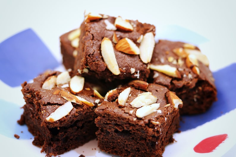 Peut inclure: Une assiette de brownies au chocolat garnis d'amandes effil&eacute;es. Les brownies sont d'une couleur brun fonc&eacute; riche et les amandes sont d'un blanc cr&eacute;meux clair.
