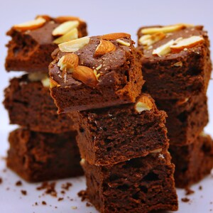 Peut inclure: Une pile de brownies au chocolat garnis d'amandes. Les brownies sont d'une couleur brun fonc&eacute; riche et ont une texture l&eacute;g&egrave;rement croustillante. Les amandes sont de couleur brun clair et ajoutent une texture croquante aux brownies.