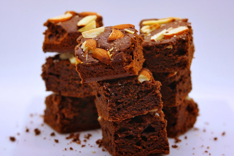 Peut inclure: Une pile de brownies au chocolat garnis d'amandes. Les brownies sont d'une couleur brun fonc&eacute; riche et ont une texture l&eacute;g&egrave;rement croustillante. Les amandes sont de couleur brun clair et ajoutent une texture croquante aux brownies.