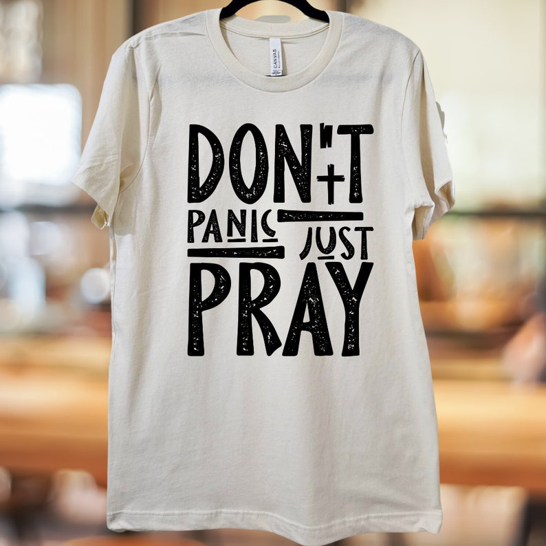 May include: A white t-shirt with black text that reads "Don't Panic Just Pray".