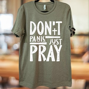 May include: A green t-shirt with the text "DON'T PANIC JUST PRAY" in white distressed lettering.