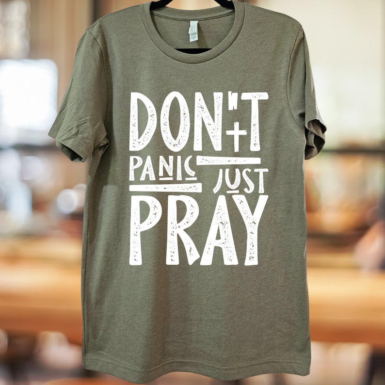 May include: A green t-shirt with the text "DON'T PANIC JUST PRAY" in white distressed lettering.