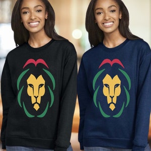 May include: Two sweatshirts with a lion graphic. The sweatshirt on the left is black with a green, red, and yellow lion graphic. The sweatshirt on the right is navy blue with a green, red, and yellow lion graphic.