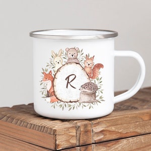 May include: White enamel mug with a woodland animal design. The design features a fox, bear, rabbit, squirrel, and hedgehog around a tree stump with the letter "R" on it.