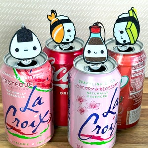 Pu&ograve; includere: Quattro lattine di alluminio di bevande gassate La Croix con diversi gusti. Ogni lattina ha un diverso tappo per bottiglia a tema personaggio, tra cui un rotolo di sushi, una bottiglia di salsa di soia e due onigiri.