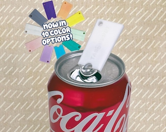 May include: A white plastic TabBuddy tool attached to the metal pull tab of a red Coca-Cola soda can. A circular display shows ten different colored versions of the same tool with the text "now in 10 color options!" printed in the center.