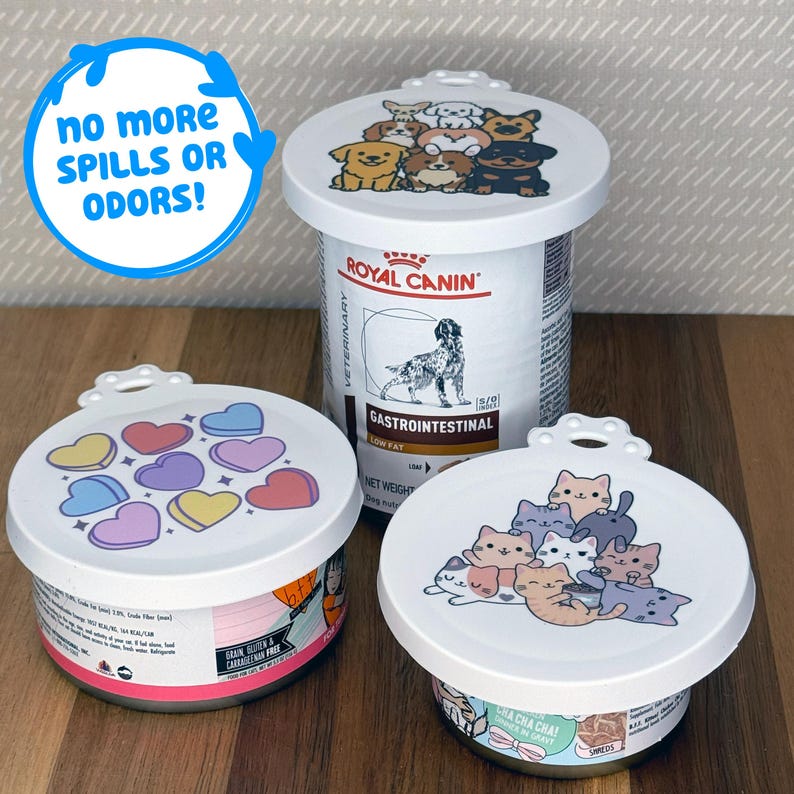 May include: Three white plastic pet food can lids with decorative prints. One lid features cartoon dogs, one has colorful hearts, and one displays cartoon cats. A blue circular graphic with the text NO MORE SPILLS OR ODORS! is visible.