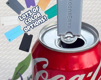 May include: A light gray TabBuddy can opener tool attached to the metal tab of a red soda can. The image includes the text LOTS OF COLOR OPTIONS! and displays several additional TabBuddy tools in white, blue, black, purple, orange, and green.