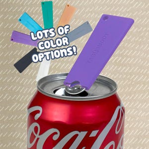 Puede incluir: Un abrelatas TabBuddy morado está sujeto a la anilla de una lata de refresco roja. Varias herramientas TabBuddy más en negro, blanco, azul, verde, melocotón y gris están dispuestas en abanico arriba, con el texto LOTS OF COLOR OPTIONS! visible.