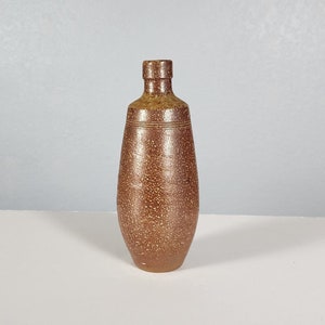 Op de afbeelding: Een bruine keramische vaas met een gespikkelde textuur en een licht uitlopende opening.