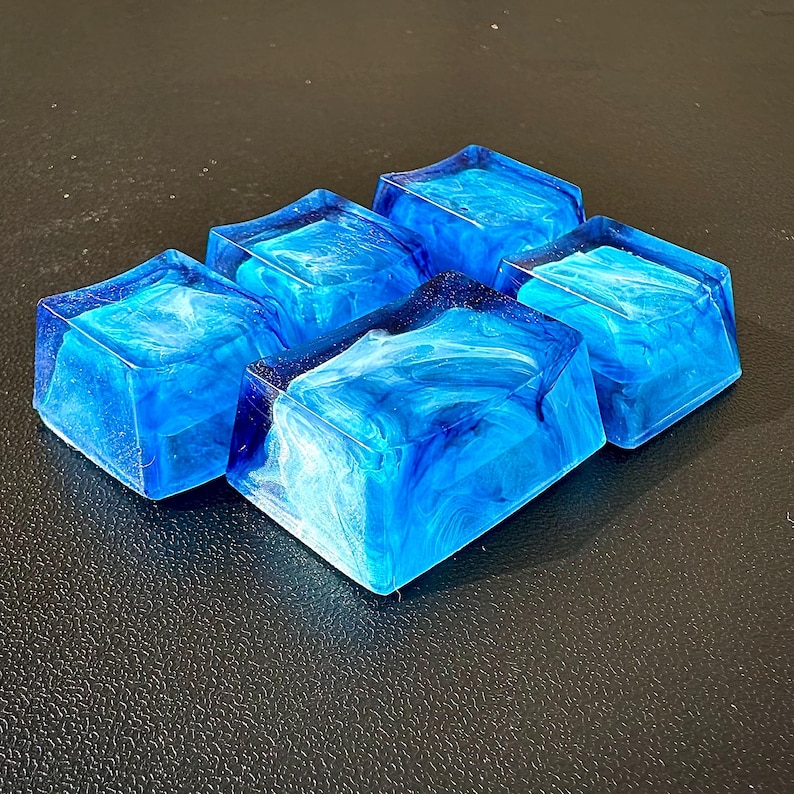 Pu&ograve; includere: Cinque tasti in resina blu con un motivo bianco a spirale. I tasti sono quadrati e hanno una finitura lucida.