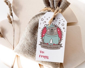 May include: A white gift tag with a cartoon bear wearing a blue and white sweater and a red hat. The tag has the text "Happy Holidays" and spaces for "To:" and "From:".