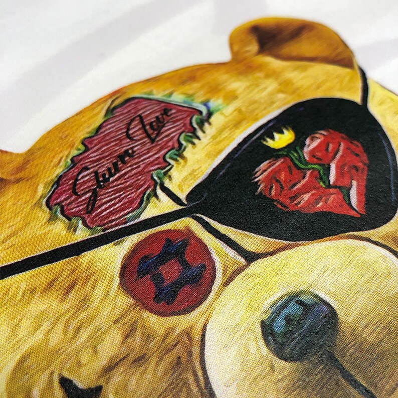 May include: A yellow teddy bear with a black eye patch and a red heart with a crack in it. The bear has a red tattoo that says "Gummy Love" and a red tattoo with a blue and black symbol.