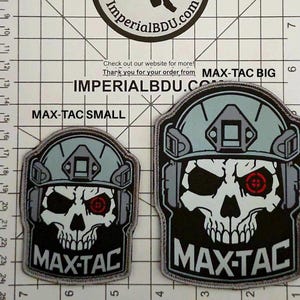 Könnte beinhalten: Zwei gestickte Aufnäher mit einem Totenkopf-Design, der einen Helm trägt und ein rotes Ziel im Auge hat. Der Text "MAX-TAC" steht darunter. Einer ist mit "MAX-TAC SMALL" und der andere mit "MAX-TAC BIG" beschriftet.