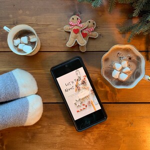 May include: A cosy winter scene with a cup of hot chocolate topped with marshmallows, a book titled "Let's Talk About Mimosas", and a pair of striped socks.