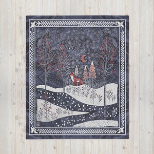 Könnte beinhalten: Eine blaue und weiße gemusterte Wolldecke mit einer Winterszene, die einen Fuchs zeigt, der durch einen schneebedeckten Wald mit Bäumen und einem Halbmond am Himmel geht.
