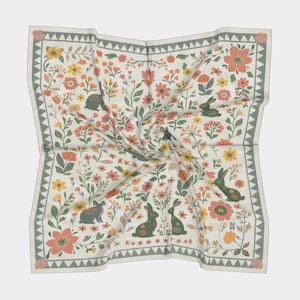 May include: A white square scarf with a floral pattern featuring green leaves, orange, pink, and yellow flowers, and small green rabbits. The border of the scarf is a green and white geometric pattern.