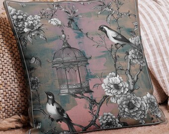 May include: Square decorative pillow with a floral and bird design. The pillow features a gray and white bird perched on a branch with flowers and a birdcage against a pink and teal background. The pillow has a gray border.