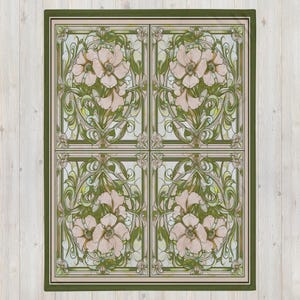 May include: A rectangular throw blanket featuring a repeating four-panel grid design. Each panel displays light pink flowers with green stems and leaves, framed by dark green and beige borders in a symmetrical, intricate botanical pattern.