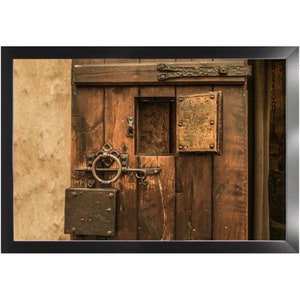 May include: A close-up of a wooden door with a metal latch and a small wooden door with a metal plate. The door is brown and has a rustic look.