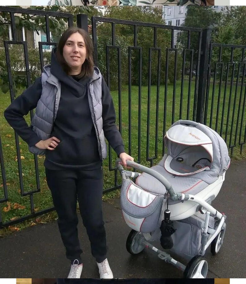 May include: A grey and white baby stroller featuring a protective canopy with the text 'AVENIR' in orange, a matching storage bag attached to the handle, and a white frame with four wheels, designed for transporting an infant in a seated position.