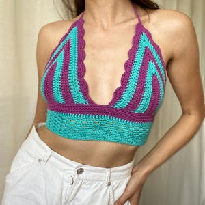 Peut inclure: Un haut dos nu en crochet arborant un motif vibrant de rayures verticales alternant entre le violet et le turquoise. Le vêtement présente un décolleté en V profond avec un bord festonné et une large bande turquoise ajourée à la base.