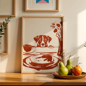 May include: A framed print featuring a dog peering over a table set with a plate, cup, and vase of flowers. The artwork is in shades of brown and cream, with a wooden frame. Two green pears and an orange sit on a wooden plate.