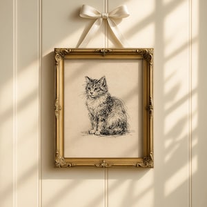 Puede incluir: Un boceto de gato enmarcado en un marco dorado ornamentado, colgado de un lazo de cinta blanca. La obra de arte presenta un dibujo detallado a pluma y tinta de un gato sentado con un pelaje esponjoso. El fondo es de color beige claro.