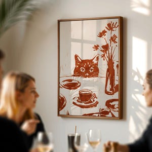 May include: A framed wall art print featuring a cat peering over a table set with a cup and saucer, plates, and a vase of flowers. The artwork is in shades of brown and white, with a wooden frame.