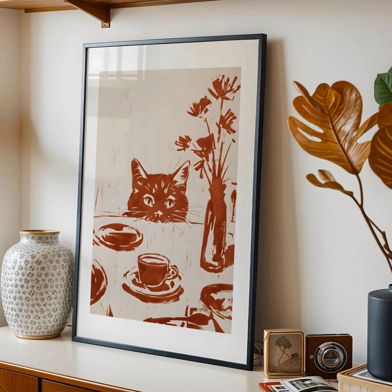 May include: Framed art print featuring a cat peeking over a table set with a cup of coffee, plates, and a vase of flowers. The artwork is rendered in shades of brown and beige, creating a warm, inviting aesthetic. The black frame adds a modern touch.