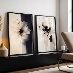 Könnte beinhalten: Zwei gerahmte Kunstdrucke mit Blumenmotiven. Jedes zeigt eine große, abstrakte Blume in Creme-, Schwarz- und Grautönen. Das Kunstwerk ist vor einem Hintergrund aus vertikalen Streifen und Spritzern angeordnet. Die Rahmen sind schwarz, und der Gesamtstil ist modern und minimalistisch.