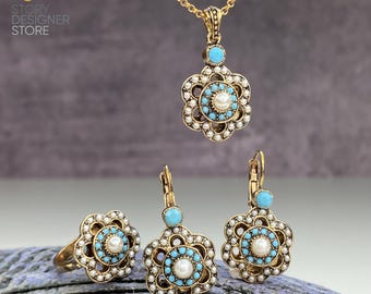 May include: A gold necklace, ring, and earrings set with a floral design. The jewelry features blue and white stones.