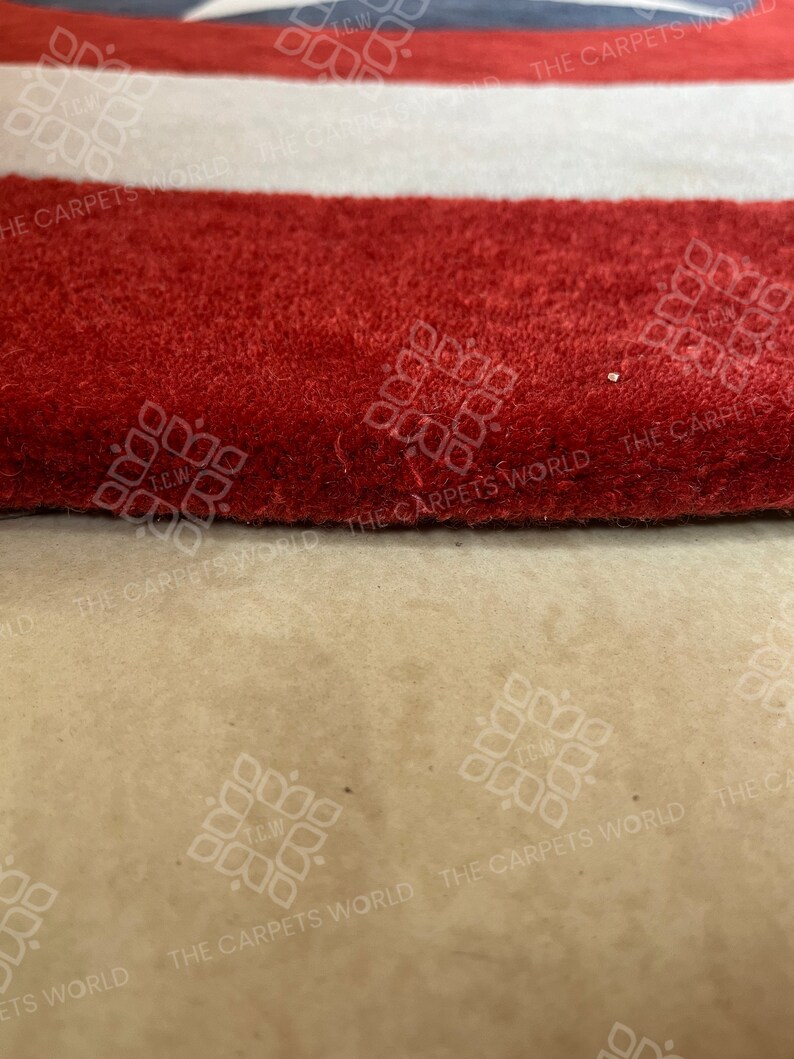 May include: Close-up of a red, white, and blue striped rug with the text "THE CARPETS WORLD" repeated on the rug.