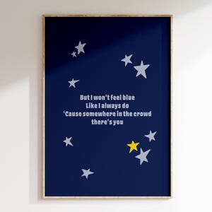 Puede incluir: Una impresión artística enmarcada con un fondo azul marino y estrellas blancas. El texto dice: "But I won't feel blue Like I always do 'Cause somewhere in the crowd there's you." Una estrella es amarilla. Decoración del hogar.