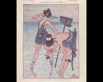 May include: A vintage illustration titled LA VIE PARISIENNE LES BELLES ET LA BÊTE by A. Vallée. It depicts two figures in swimwear standing in shallow water, one holding a net and the other examining a small crab. The text reads Vous allez nous photographier : nous avons pêché un crabe!