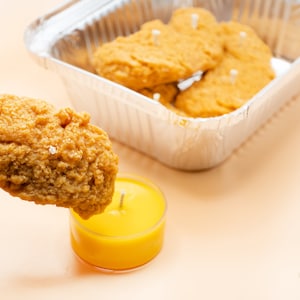 One of the chicken tender candles is taken out as if it is going to be tipped into the mustard sauce.