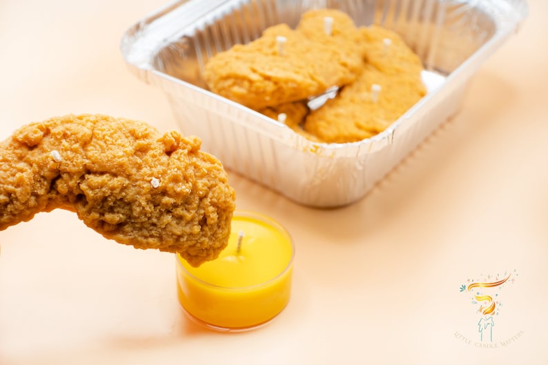 One of the chicken tender candles is taken out as if it is going to be tipped into the mustard sauce.