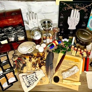 May include: A collection of various witchcraft and pagan supplies, including herbs, crystals, candles, a cauldron, a dreamcatcher, a book on palm reading, and a wooden box with compartments.