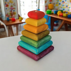 Puede incluir: Un juguete de apilar de madera de colores arcoíris con siete bloques. Los bloques son cuadrados y tienen un acabado liso y pintado. Los colores de los bloques son rojo, amarillo, naranja, verde, azul, morado y turquesa.