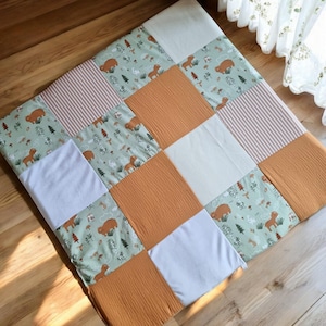 以下が含まれることがあります： ストライプ、白、茶色のクマと木が描かれた緑の模様など、さまざまなパターンが施されたパッチワークプレイマット。 プレイマットは柔らかな生地で作られており、赤ちゃんや幼児に最適です。