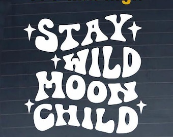 May include: A white vinyl decal featuring the text STAY WILD MOON CHILD in a bold, wavy font, accented by four-pointed stars. The decal is 100 mm high and is displayed against a dark, horizontally lined surface, creating a high-contrast visual.